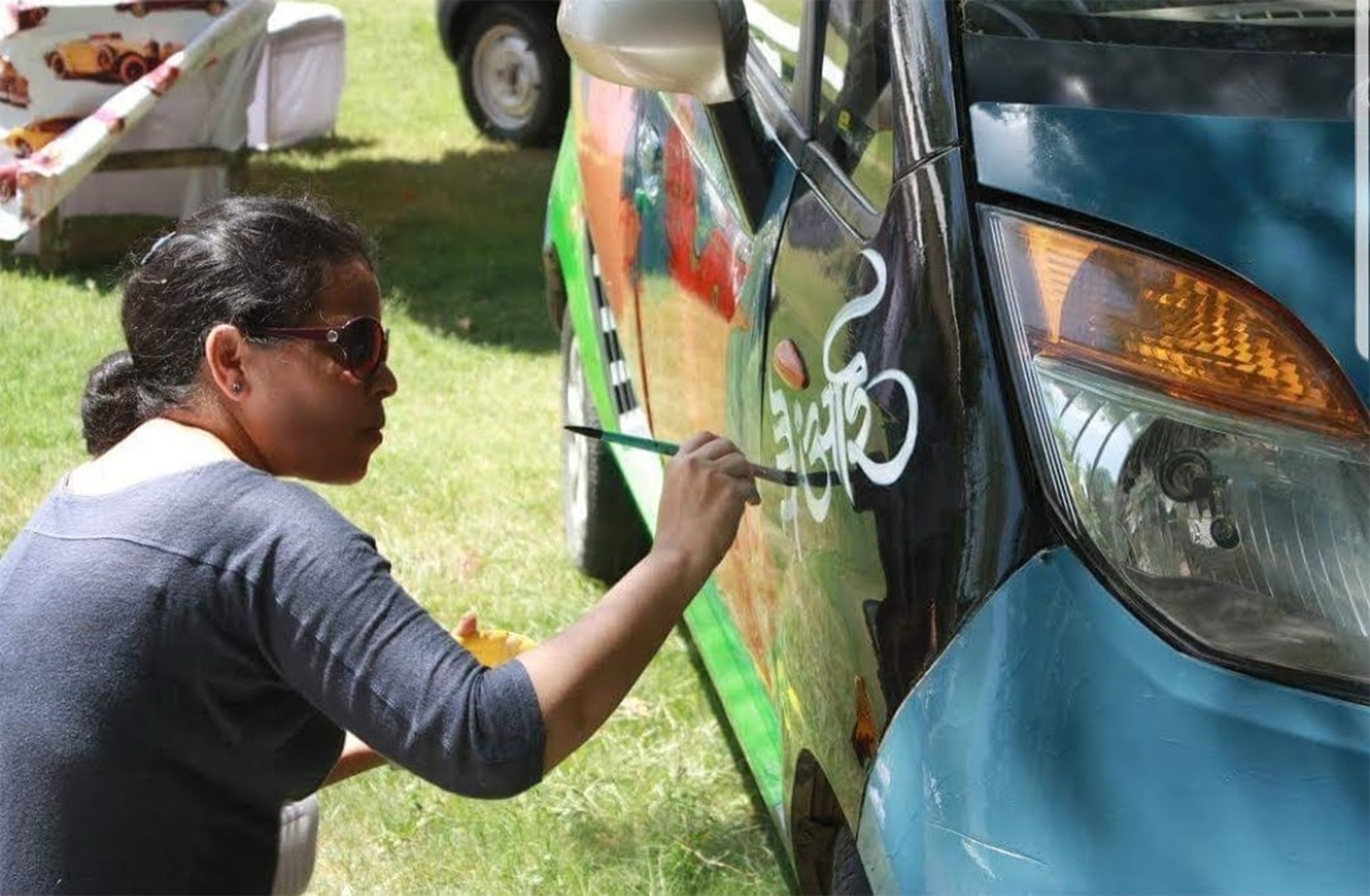 Calligrapher hand-painting lettering onto a car at the Cartist Jaipur classic and vintage car event