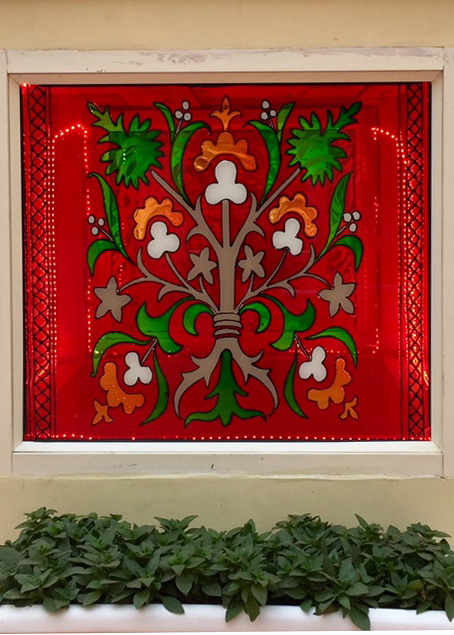 Decorative stained glass window with a tree motif at Dak Bhawan